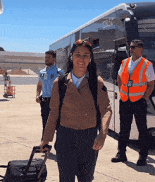 a woman carrying a suitcase walks past a cobus bus
