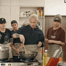 a group of men are cooking in a kitchen and one of them is wearing a shirt that says golden sizzling