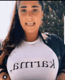 a woman wearing a white t-shirt that says " kallus " is smiling