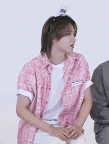 a man wearing a pink plaid shirt has a name tag that says ' sung ' on the front