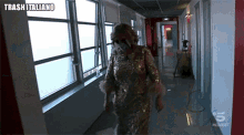 a woman in a sequined dress is walking down a hallway with trash italiano on the bottom