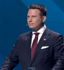 a man in a suit and tie with a red white and blue flag on his chest