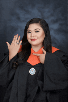 a woman in a graduation cap and gown points to her ring