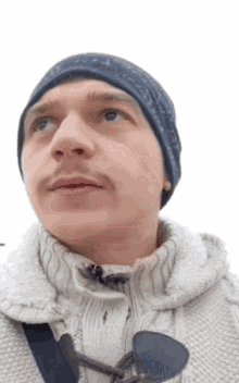 a man wearing a hat and a sweater looks up