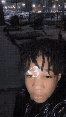 a young man with dreadlocks has a 3 on his forehead