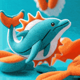 a blue and orange stuffed dolphin with a sun on its back