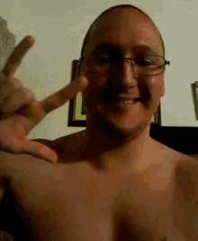 a shirtless man wearing glasses is giving the peace sign