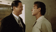 a man in a suit and tie is talking to another man