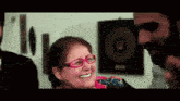 a woman wearing glasses is smiling and talking to a man .