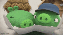 two green pigs wearing hats are hugging each other on a table .