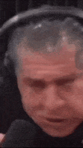 a man wearing headphones is talking into a microphone and making a funny face .