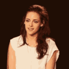 a woman with long hair is wearing a white shirt and a necklace .