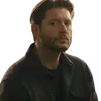 a man with a beard is wearing a black shirt and a brown jacket
