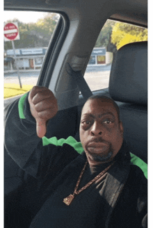 a man is giving a thumbs down sign while sitting in a car