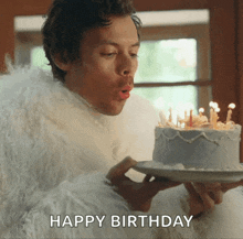 a man in a fur coat blows out candles on a birthday cake that says happy birthday