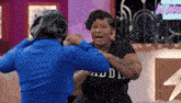 a woman in a black shirt with the word audi on it is fighting another woman in a blue shirt