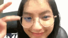 a young woman wearing glasses is making a peace sign .
