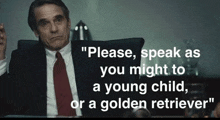 a man in a suit and tie says " please speak as you might to a young child or a golden retriever