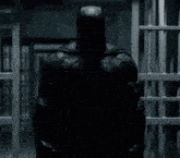 a man in a batman costume is standing in a jail cell