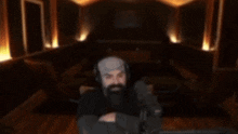 a man with a beard is sitting in front of a microphone with his arms in the air