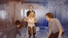 a group of people are standing in a room covered in blue paint .