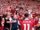 a man wearing a red jersey with the number 11 on it stands in front of a crowd