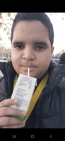 a boy is drinking from a carton with a straw in his mouth