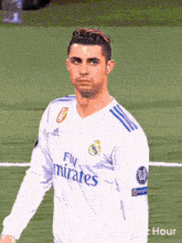 a man wearing a fly emirates jersey stands on a soccer field