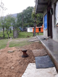 a drum sits in the dirt outside a house