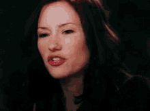 a woman with long dark hair is smiling and making a funny face .
