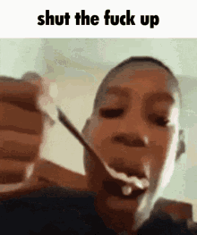 a man holding a spoon in his mouth with the words shut the fuck up below him