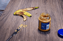 a jar of peanut butter and a banana peel on a wooden table