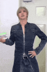 a man in a denim jacket is holding a green container