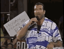 a man is holding a microphone and holding a sign that says hogan fears my beard .