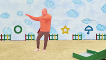 a man in an orange hoodie stands with his arms outstretched in front of a wall with drawings of clouds and a star