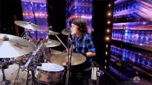 a man playing drums on a stage with a nbc logo in the background