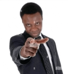 the man is wearing a suit and tie and pointing at the camera .
