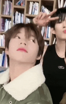 a man and a woman are standing next to each other in front of a bookshelf in a library .