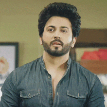 a man with a beard wears a blue shirt