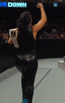 a woman is standing on a stage with her arms in the air in front of a sign that says ' ck down '
