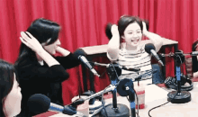 a group of women are sitting in front of microphones .