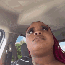 a woman with red hair is sitting in a car looking up