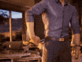 a man in a blue shirt and black pants is putting something in his pocket
