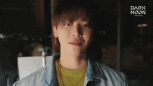 a young man is wearing a denim jacket and a yellow shirt with a dark moon logo on the bottom