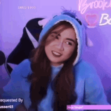 a woman wearing a blue hoodie with a shark hood is smiling .