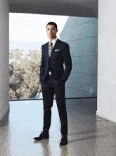 a man in a suit stands in front of a window