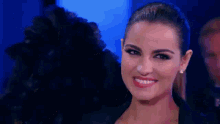 a close up of a woman 's face smiling with a man in the background .