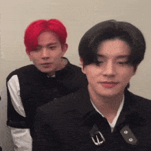 a man with red hair is standing next to another man in a black jacket
