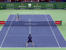 two tennis players on a court with rolex and emirates ads