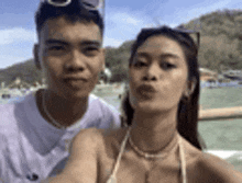 a man and a woman are posing for a selfie on the beach .